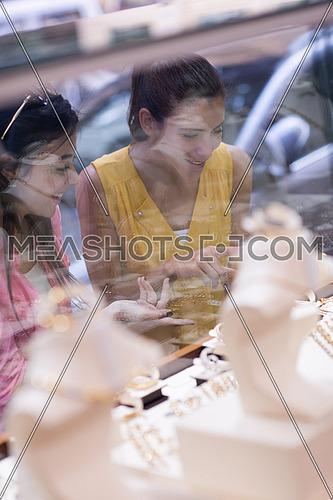 two middle eastern young women enjoy as they watch jewelry in the window of a luxury jewelry store