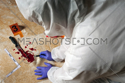 Expert Police examining with magnifying glass a knife with blood at the scene of a crime, conceptual image