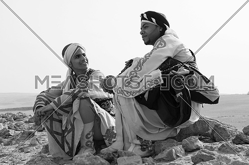 a black and white shot of two Egyptian sufi dancers sitting in the desert talking