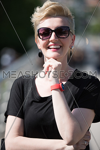 Beautiful fashionable young woman with short blond hair and sunglasses posing in the park