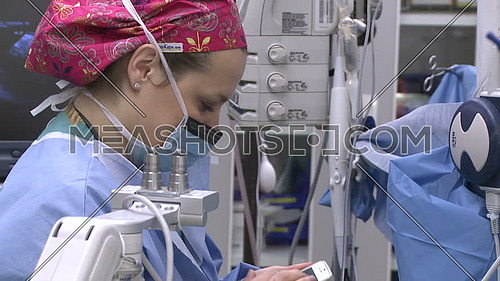 Close Shot for a Anesthesiologist uses mobile phone in operation room