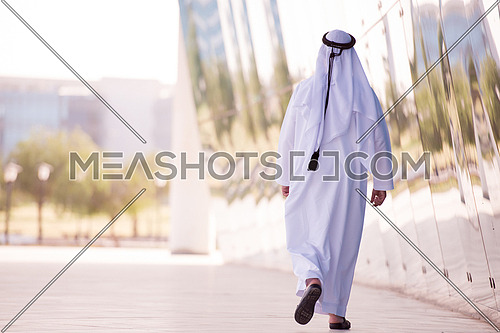 handsome middle eastern business man walking in front of modern office building