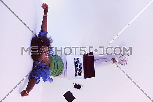 Portrait of happy young african american woman sitting on floor with laptop top view