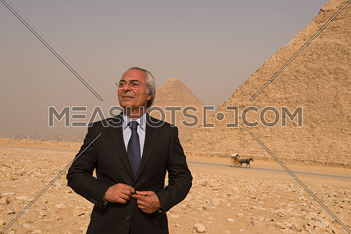 portrait of mature middle eastern business man in front of ancient egyptian pyramids