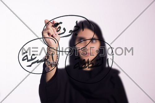 Arabian middle eastern business woman writing with a marker on virtual screen  in arabic cost, quality & speed
isolated on white background