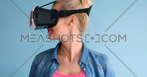 Happy girl getting experience using VR headset glasses of virtual reality, isolated on blue background