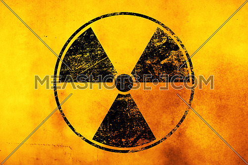 Black radioactive hazard warning sign painted over grunge yellow background with copy space