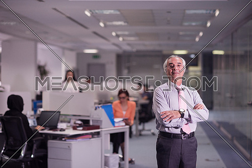portrait of senior businessman as leader  at modern office interior  young  people group in background on their workplace