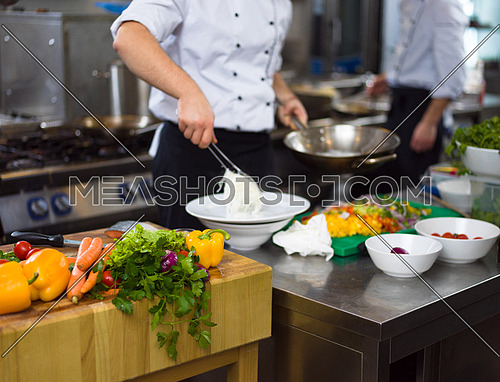 Chef hands serving spaghetti on restaurant kitchen