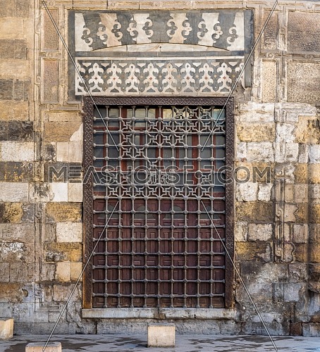 Wooden grunge window with decorated iron grid over stone bricks wall, Moez Street, Cairo, Egypt