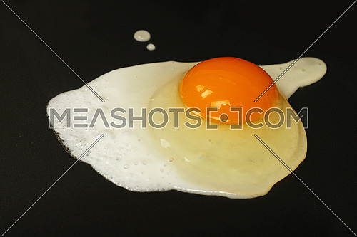 Close up cooking one sunny side fried egg on electric grill surface, high angle view