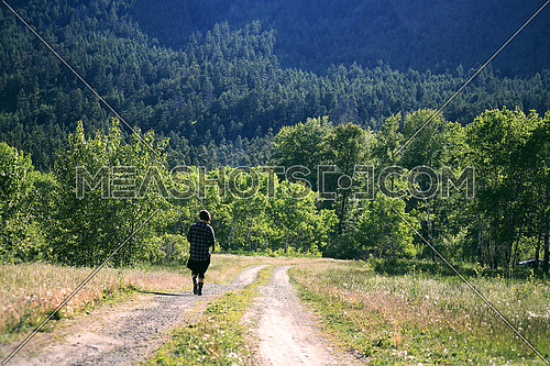 A girl walking on a path towards a forest
