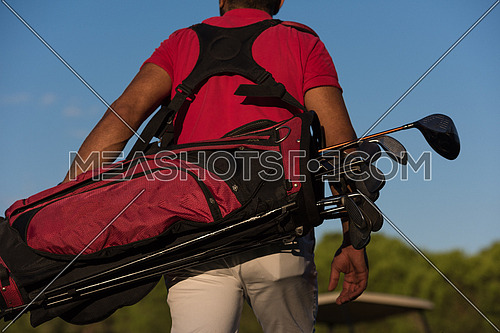 close up of golfers back while carrying  golf bag  and walking at course to next hole