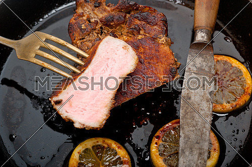 pork chop seared on iron skillet with lemon and spices seasoning