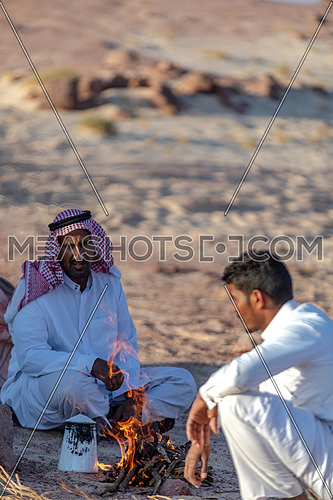 Two Bedouin Males wearing traditional clothing, sitting and making tea at Ain Hodouda area in Sinai at day.