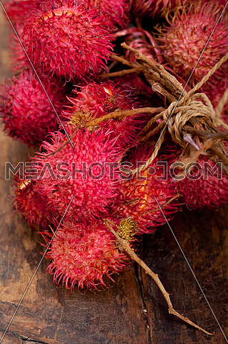 fresh tropical rambutan fruits over rustic wood table 