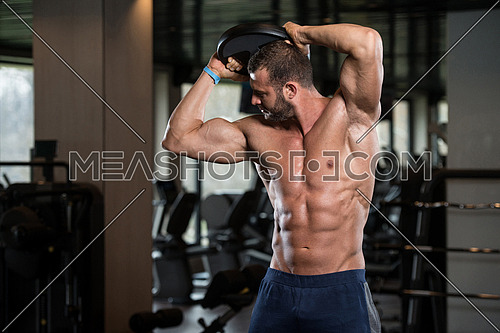 Young Man Exercising Abdominal Muscles With Weights In A Modern Fitness Club