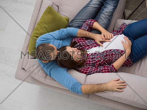 top view of happy pregnant couple relaxing on sofa couch at home