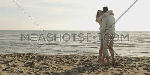 Young couple having fun on beach during autumn sunny day
