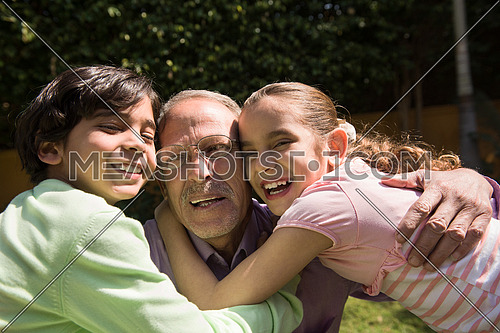 happy middle eastern grandfather enjoying with their grandchildren in the yard of a beautiful sunny day