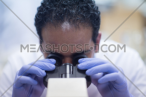 portrait of a young middle eastern man with a microscope in a large modern laboratories