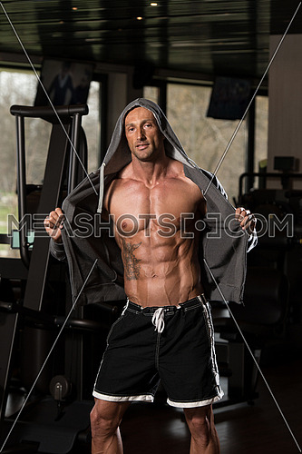 Portrait Of A Physically Fit Man In Hoodie - In Modern Fitness Center - Showing His Six Pack