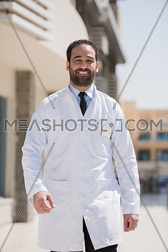 middle eastern young doctor portrait in front of modern hospital