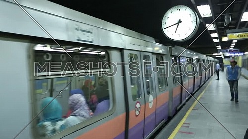 Fixed shot inside Metro Station for people walking on platform then train going out station at Cairo