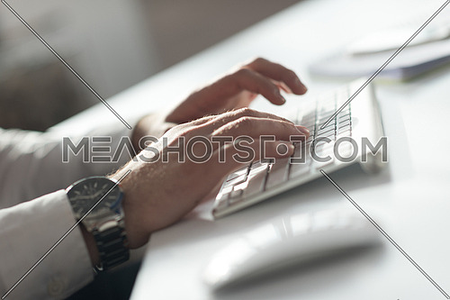 hands typing on desktop computer keyboard in modern bright office interior