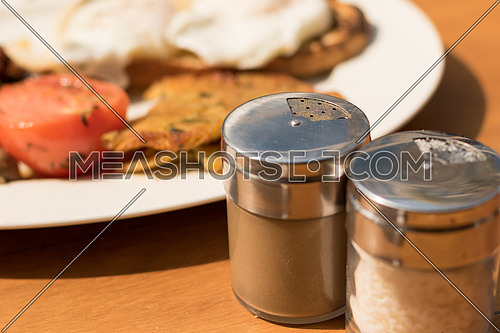 Salt and Pepper shakers on a wooden breakfast table