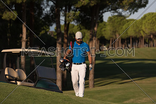 handsome middle eastern golfer  carrying  bag  and walking  to next hole at golf  course