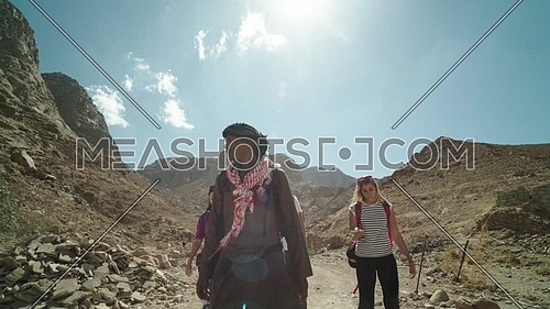 Tilt down shot for group of tourists walking with bedouin guide exploring Sinai Mountain from wadi Freij at day.
