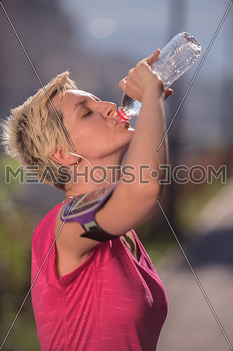 young woman drinking a water after mornig jogging workout  city  sunrise in background