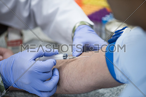 Young middle eastern Medical technologist doing a blood draw services for patient.