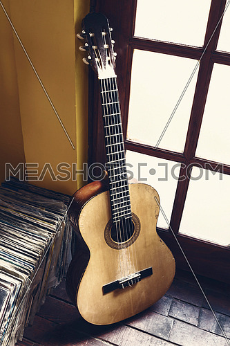 Old dusty guitar and records on the wooden flor