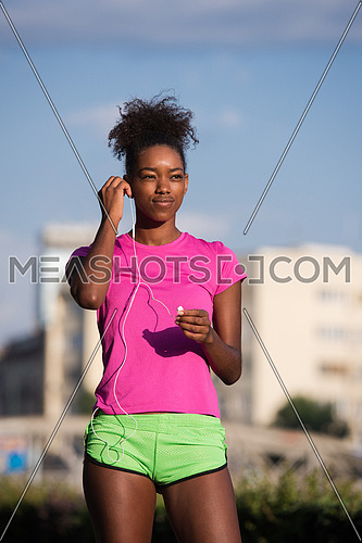 portrait of a young African American girl with headphones to run beautiful summer morning on city streets