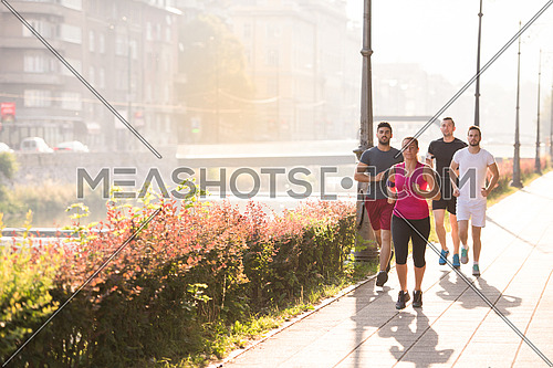 group of young sporty people jogging at sunny morning in the city