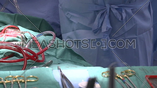 Close up shot forsurgical tray with equipments and blood pumping through tubes of bypass machine in background