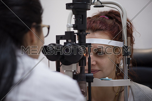 Professional middle eastern oculist is checking human vision with equipment in the modern clinic
