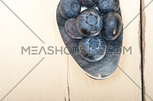 fresh blueberry on silver spoon over a white rustic wood table