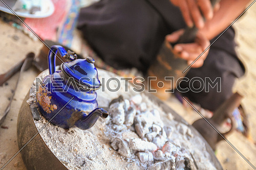 Gringing traditional Gabana Coffee and a kettle of tea on charcoal