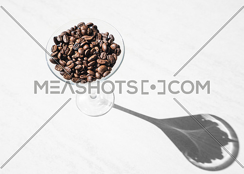 top view of coffee beans inside a glass,accentuated shadow of the glass in the sunny day, natural light.
