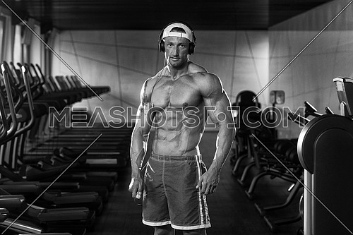 Muscular Mature Man Listening Music From His Mp3 Player In Modern Fitness Center