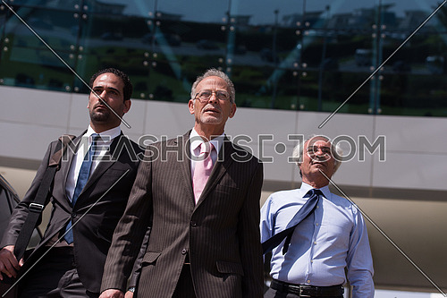 A group of business executives walking in front of a corporate building