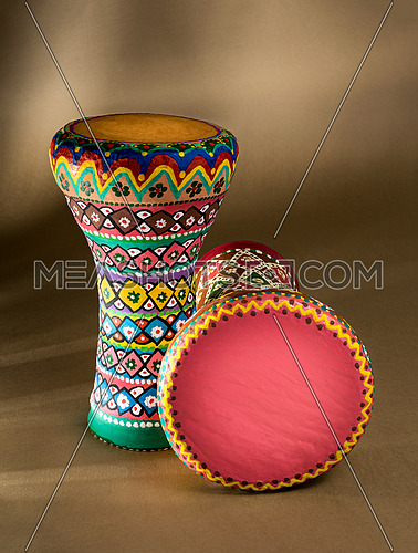 Two decorated colorful pottery goblet drums (chalice drum, tarabuka, darbuka) on background of wooden table with vanishing shadow lines. Low light