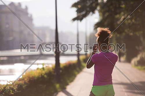 portrait of young african american jogging woman before running on early morning with sunrise in background