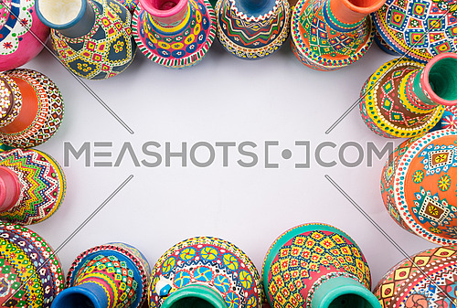 Frame of painted colorful pottery vases on white background