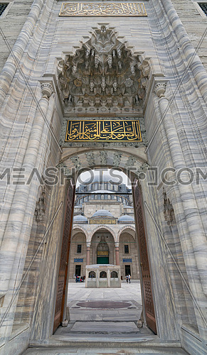 Istanbul, Turkey - April 17, 2017: Low angle day shot of one of the entrances leading to the court of Suleymaniye Mosque featuring main facade of the mosque and few tourists visiting the mosque