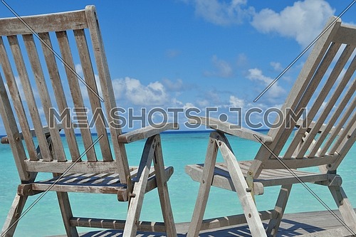 Two chairs beds in forest  on tropical beach with blue ocean in background