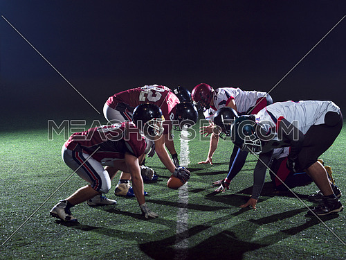 american football players are ready to start on field at night